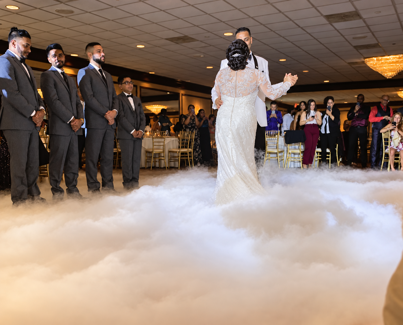Newlyweds sharing their first dance above a low cloud effect
